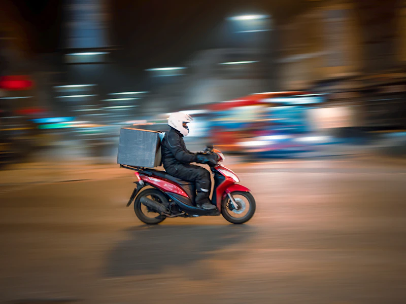 Người giao hàng chạy xe máy trên phố