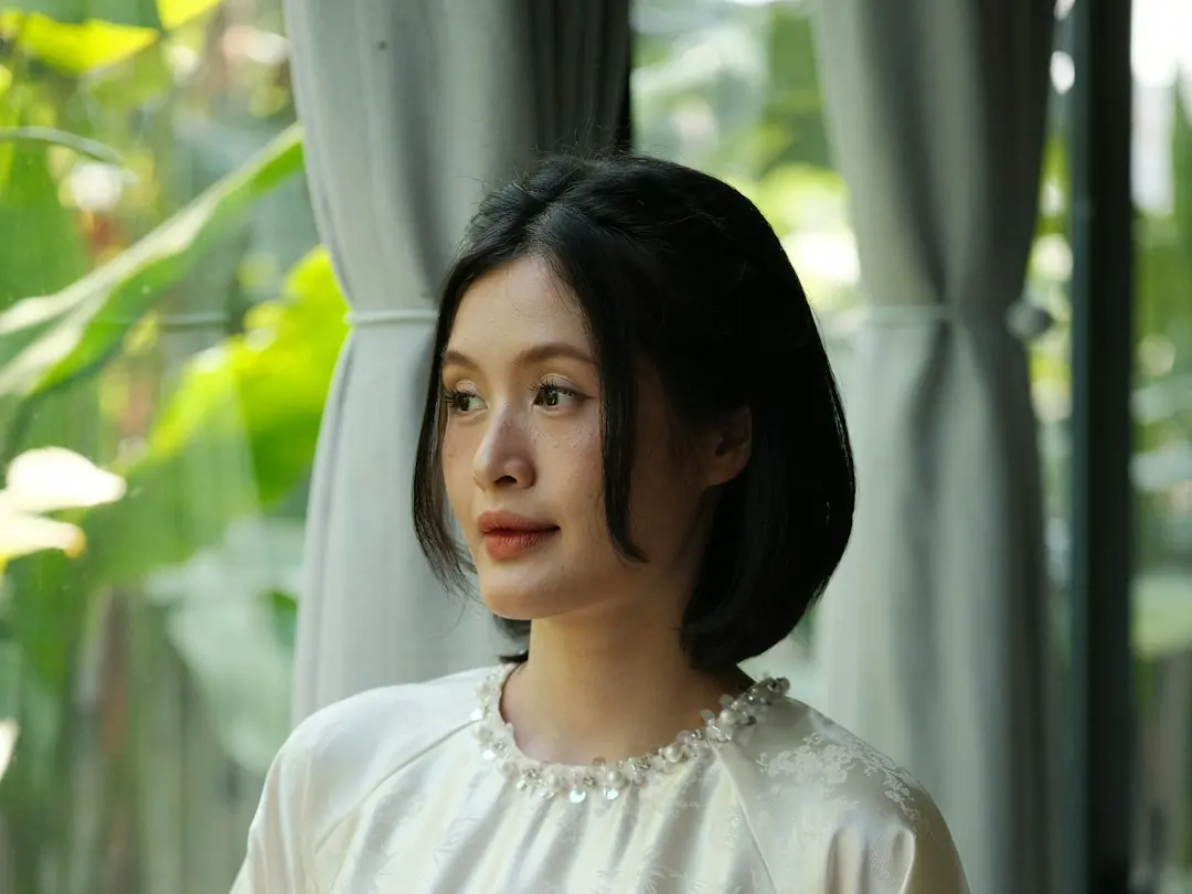 Người mẫu mặc áo lụa màu kem giữa vườn cây