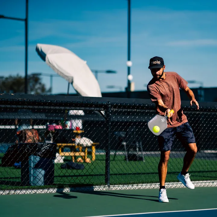 Người chơi pickleball đang đỡ bóng trên sân ngoài trời