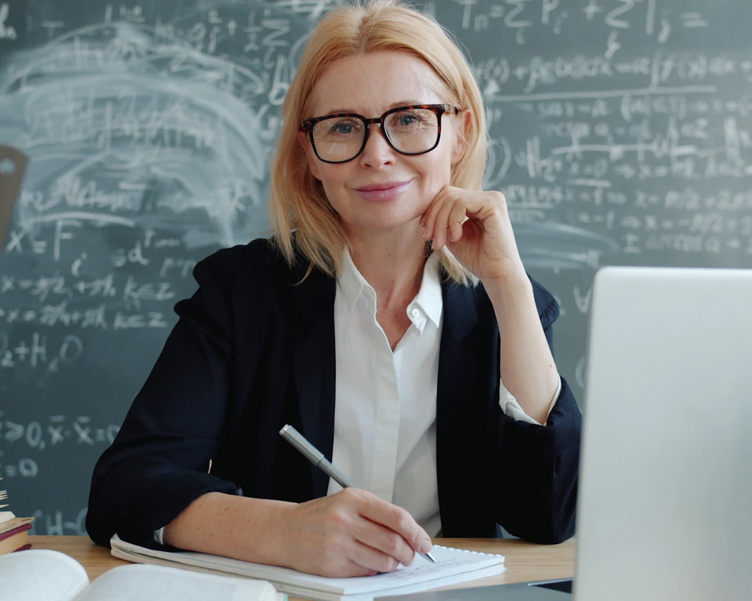 Cô giáo mỉm cười ngồi trước máy tính xách tay