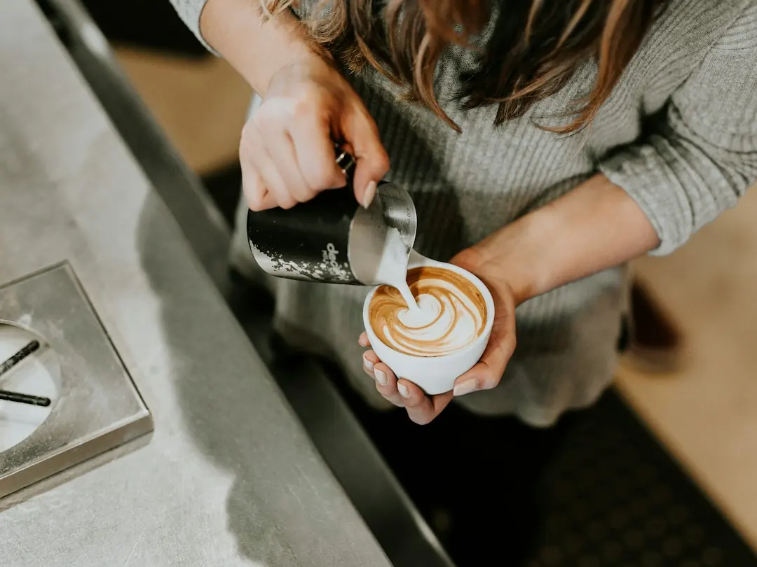 Barista rót sữa tạo hình lá lên tách cà phê